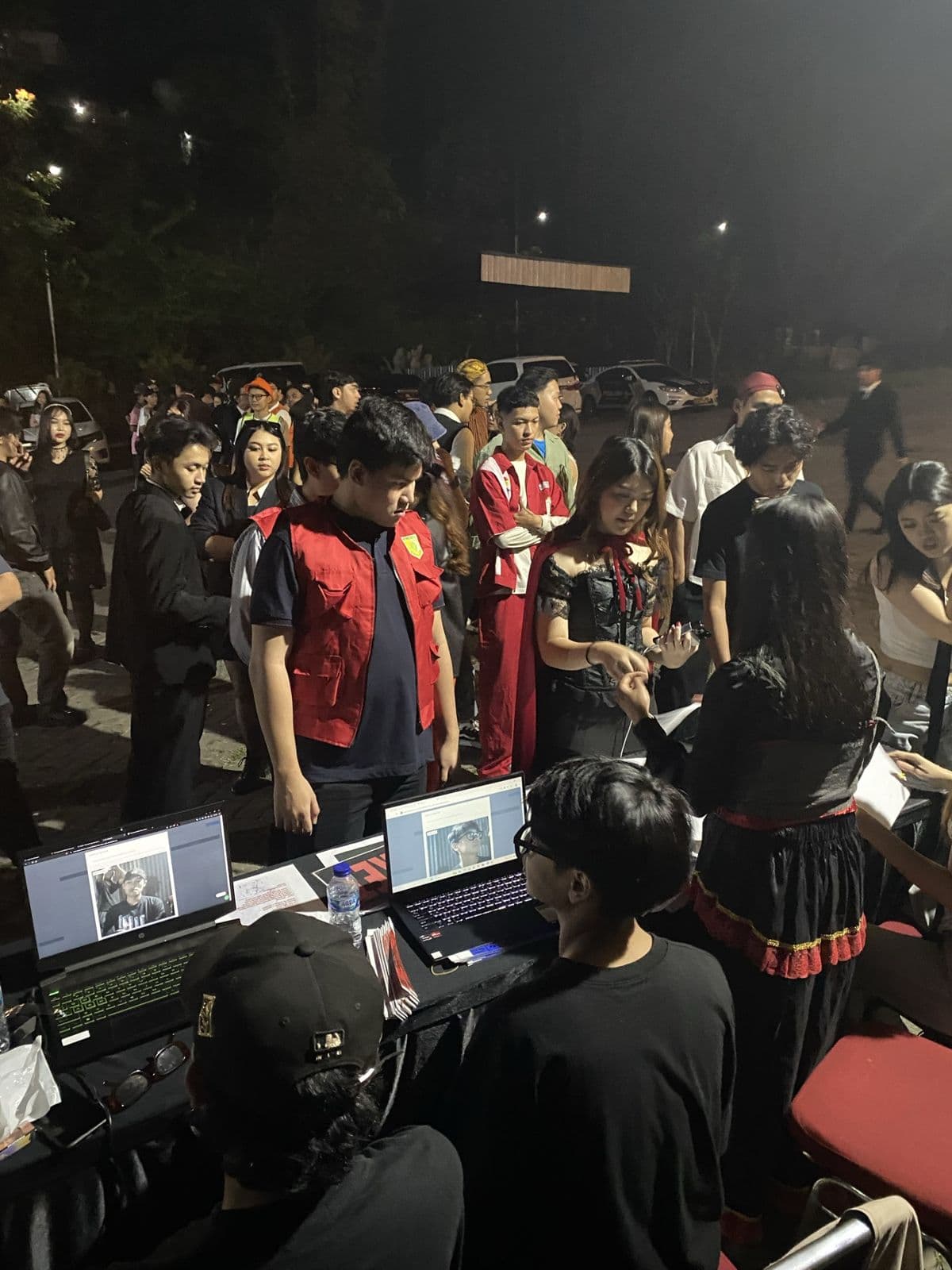 Attendees queueing at laptops for QR check-in at night